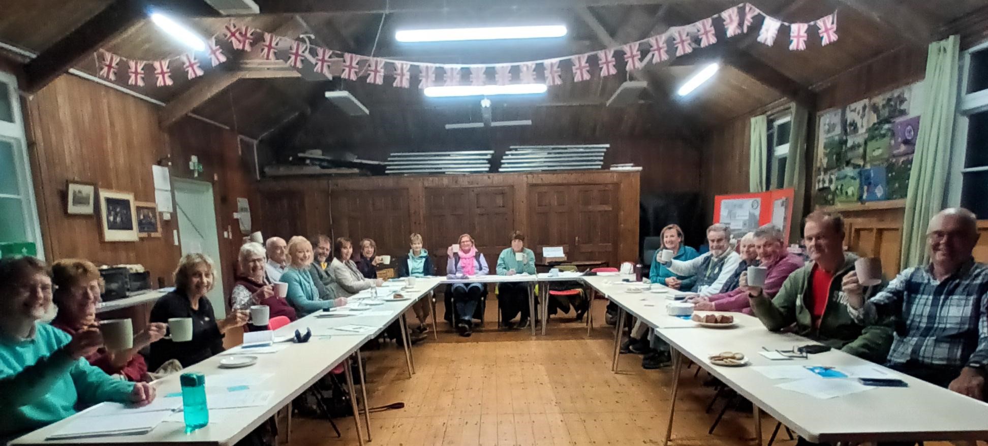 People sat around a table inside a village hall