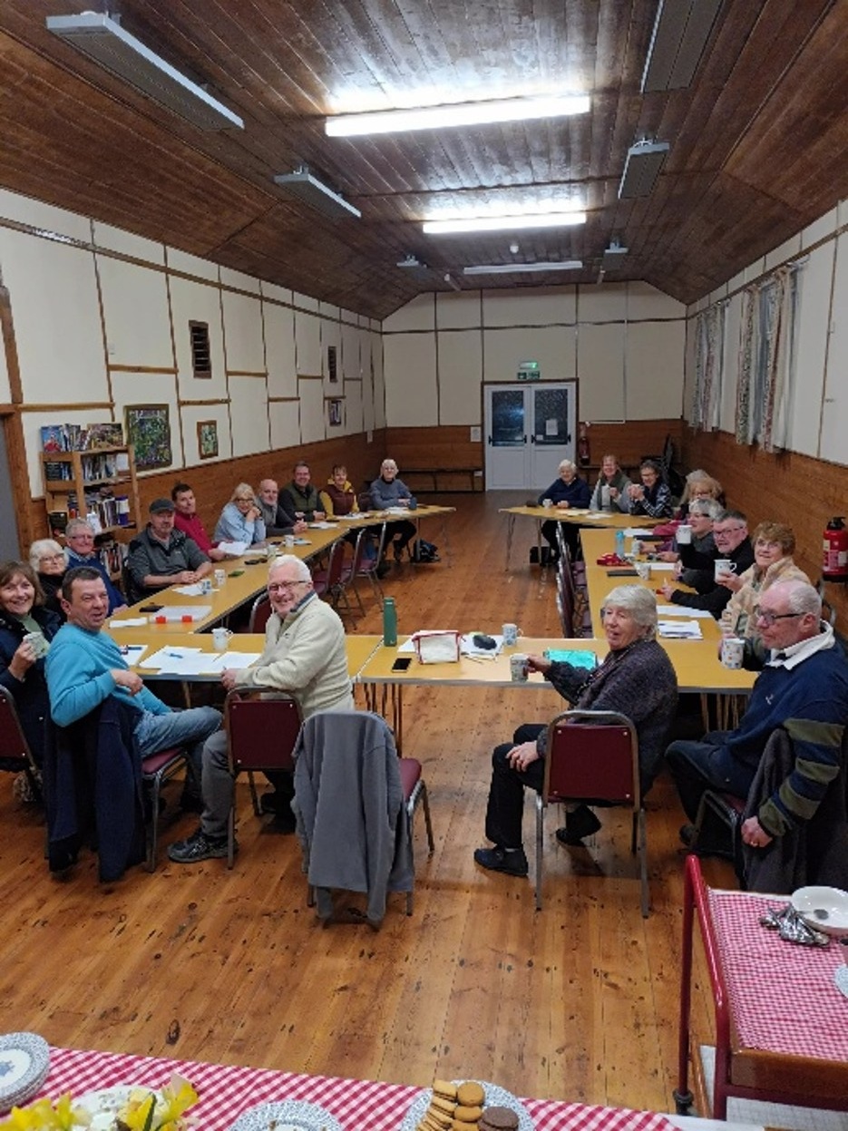people sat around a table in a village hall