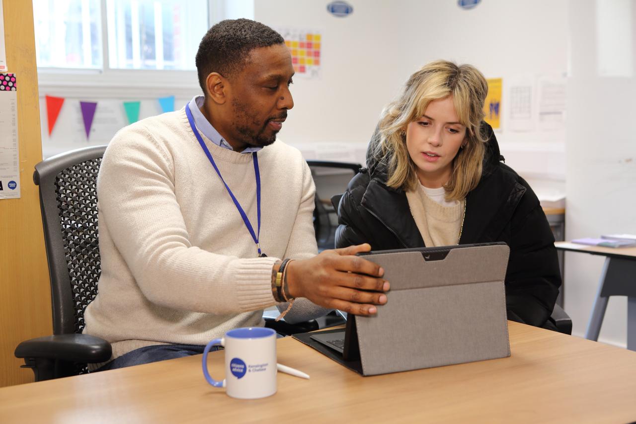 Male adviser helping young female at a laptop