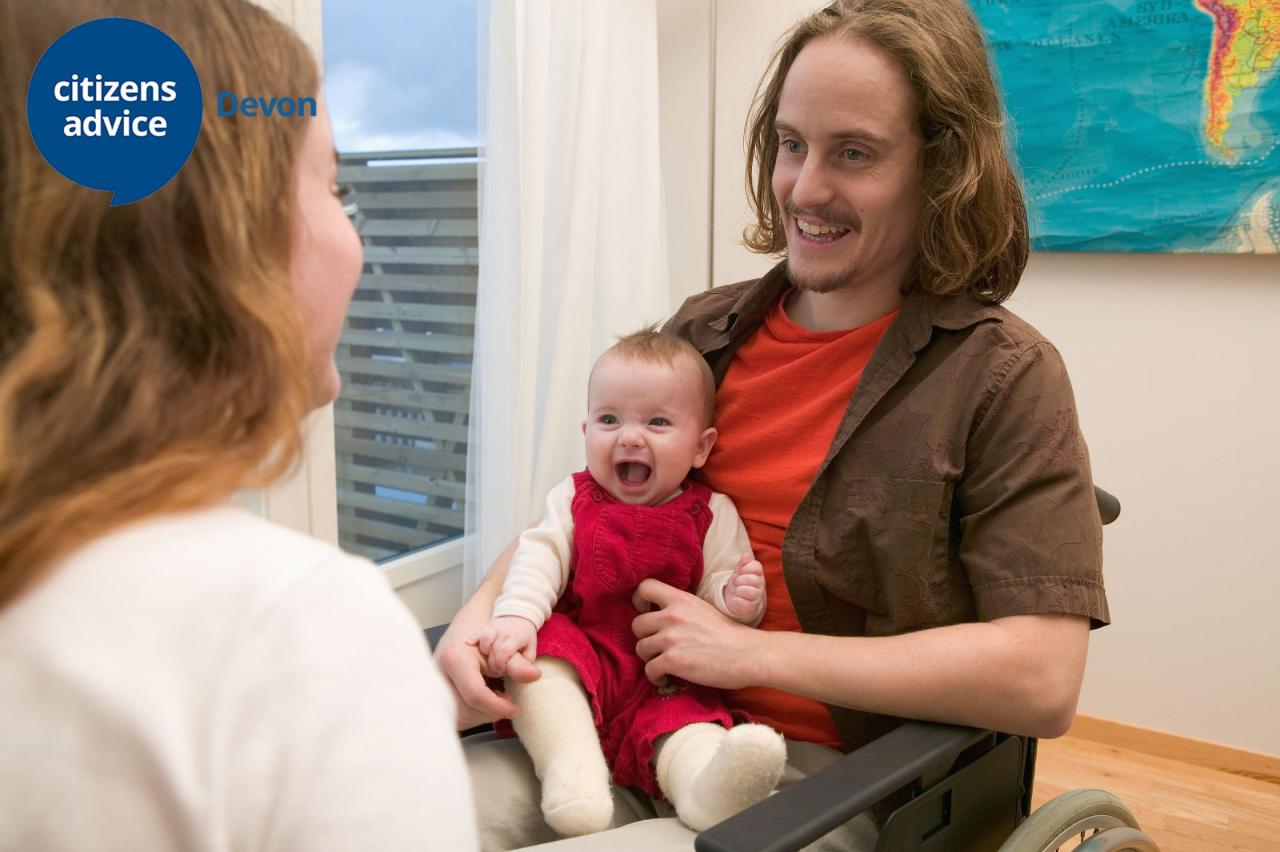 man in wheelchair holding a young child
