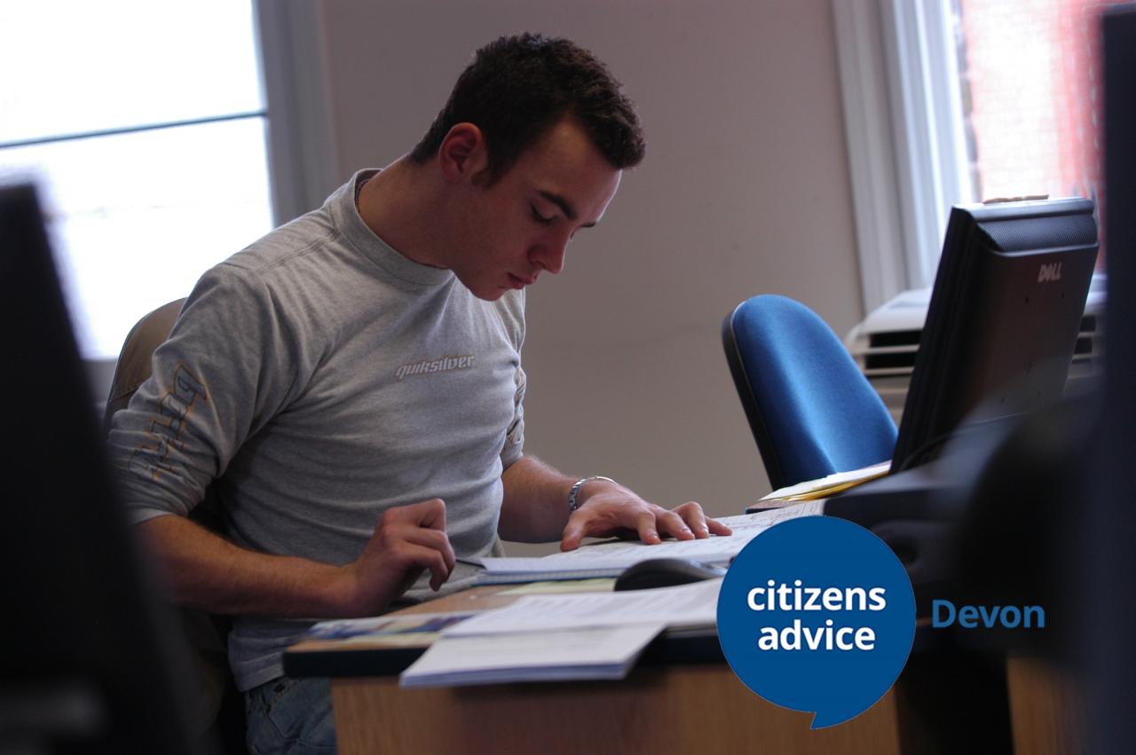 Young white adult male reading at a desk, looks like he is reviewing some information or studying