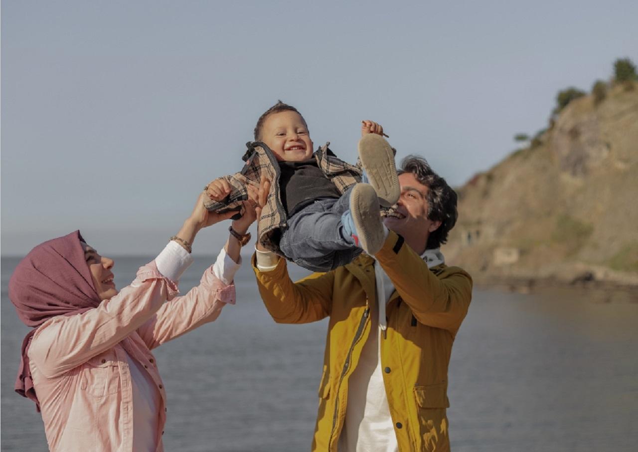 man and woman on a beach swinging a small boy in the air