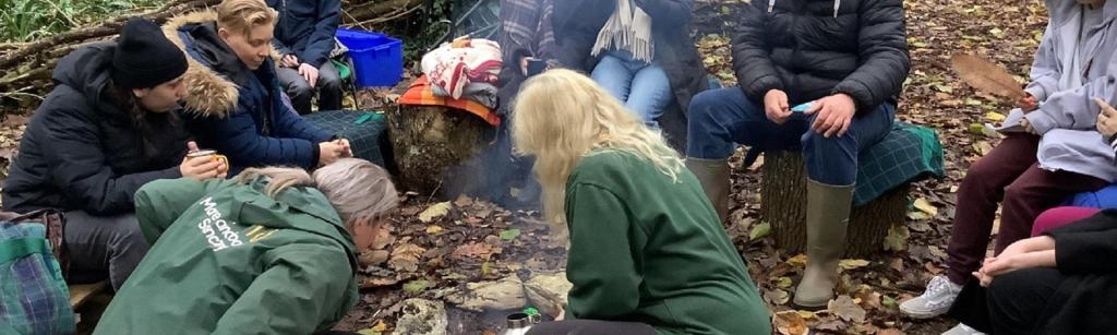 A group of young people at a small campfire