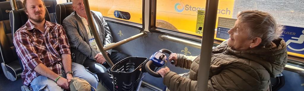 three people on a bus including a wheelchair user