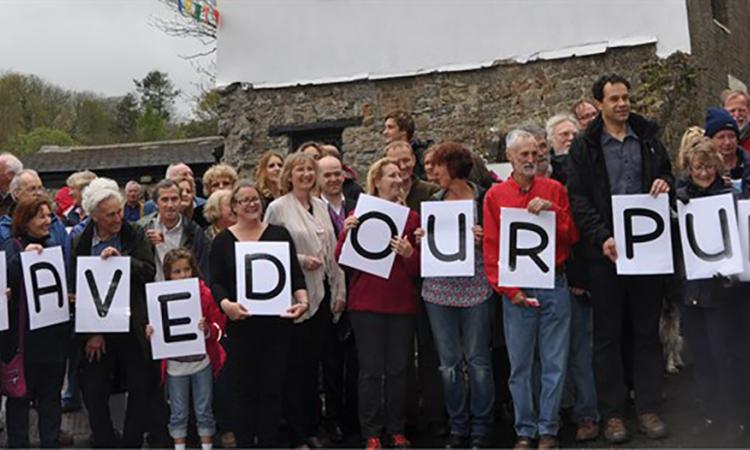 People in a line holding letters which spell "SAVED OUR PUB"