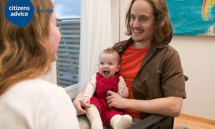 man in wheelchair holding a young child