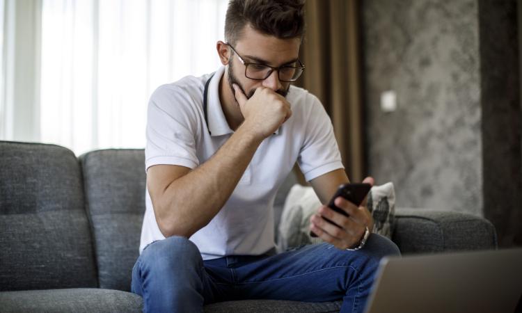Serious young adult male looking at phone