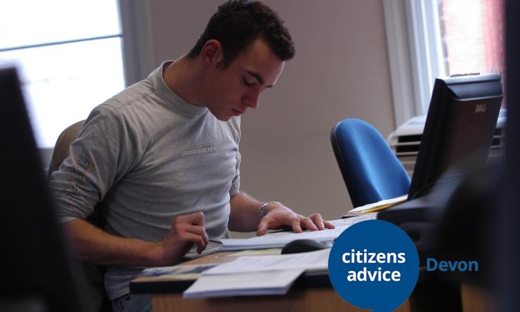 Young white adult male reading at a desk, looks like he is reviewing some information or studying