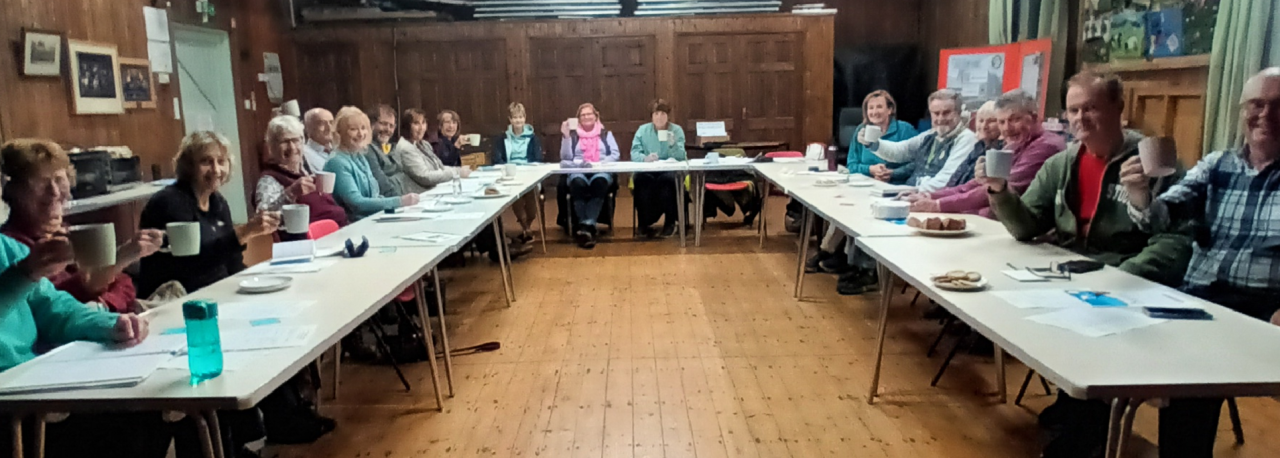people sat around a table in a village hall