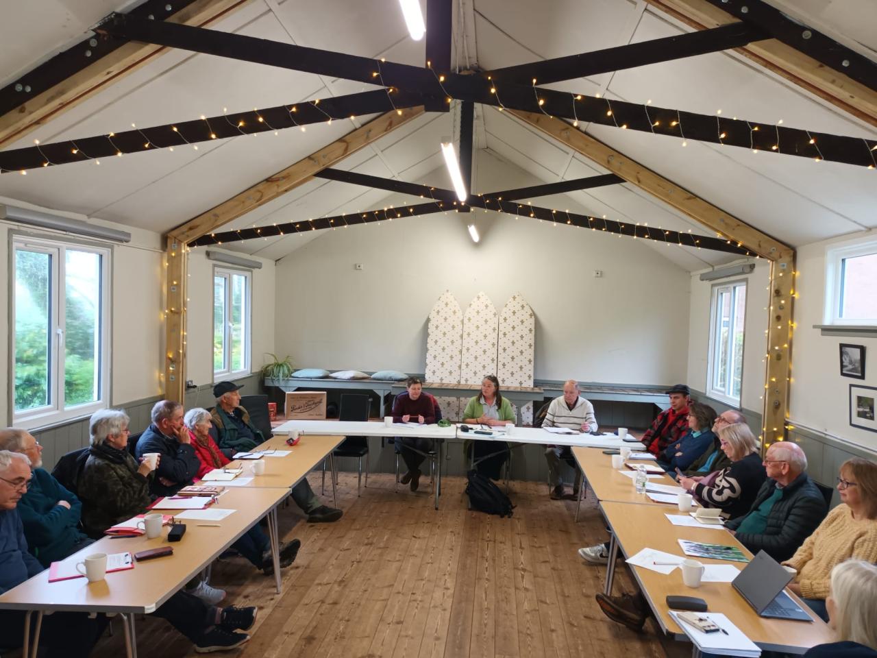 East Devon VH cluster meeting, smiling people sat in a village hall 