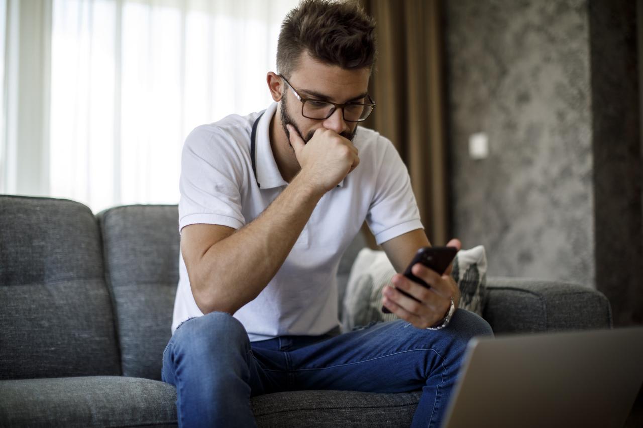 Serious young adult male looking at phone