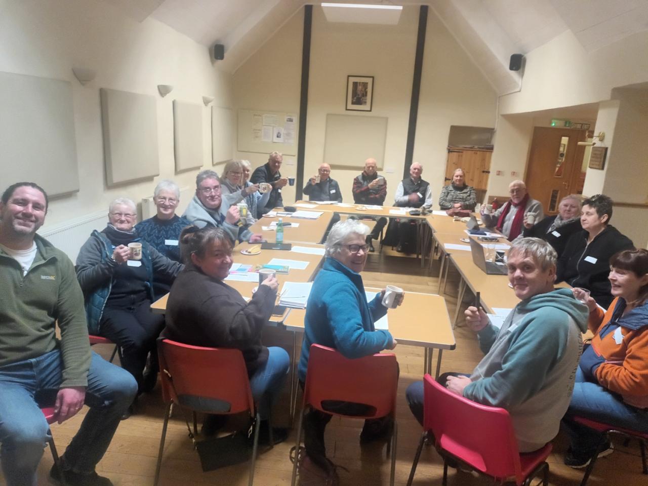 Group of smiling people sitting in a village hall 