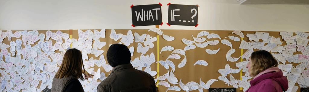 peopel looking at an ideas board that says 'what if...'