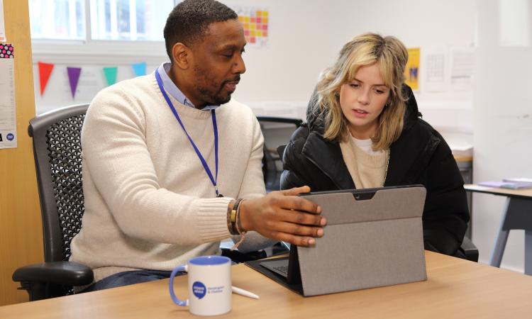 young female sat with male adviser at a table with a laptop