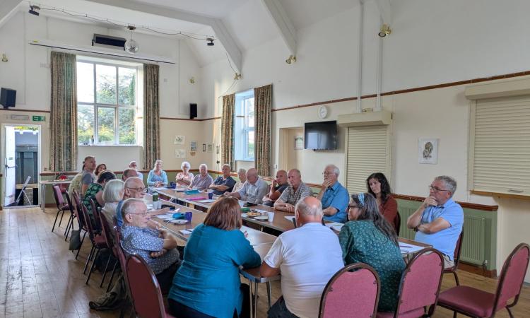 Mid Devon Cluster group meeting, group of people chatting round a table in a Village Hall