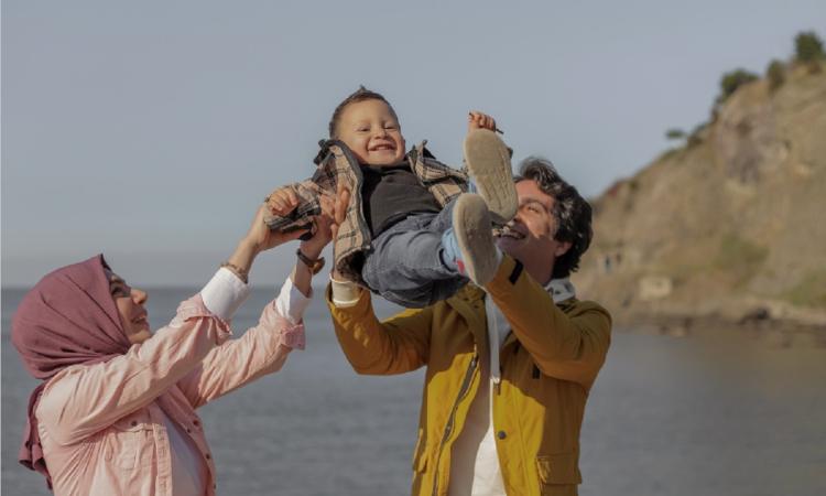 man and woman on a beach swinging a small boy in the air